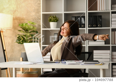 Carefree millennial businesswoman relaxing at workplace, stretching arms, taking break from work on laptop 104097788