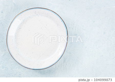 An empty white plate with a blue rim, overhead flat lay shot 104099873