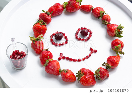 Cheerful emoticon from red berries on the white table. Cheerful emoticon from red berries on the white table. 104101879