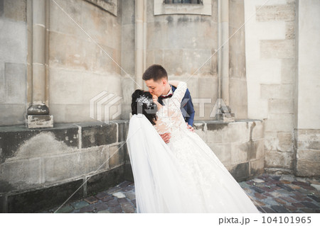 Lovely happy wedding couple, bride with long white dress posing in beautiful city 104101965