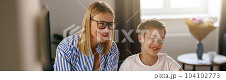 Female babysitter is teaching little boy use laptop application during studying 104102773