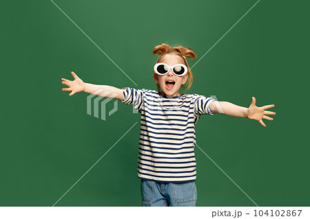 Portrait of emotiona, beautufl little girl, childin striped shirt and sunglasses posing against green studio background Portrait of emotiona, beautufl little girl, childin striped shirt and sunglasses posing against green studio background 104102867