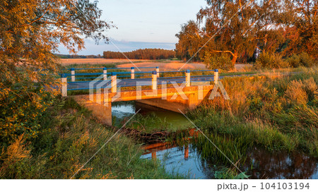 Concrete road bridge over river in sunset light 104103194