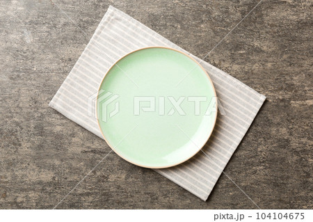 Top view on colored background empty round green plate on tablecloth for food. Empty dish on napkin with space for your design Top view on colored background empty round green plate on tablecloth for food. Empty dish on napkin with space for your design 104104675