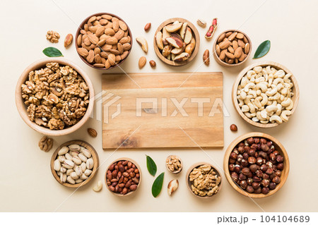 mixed nuts in wooden bowl. Mix of various nuts on colored background. pistachios, cashews, walnuts, hazelnuts, peanuts and brazil nuts 104104689