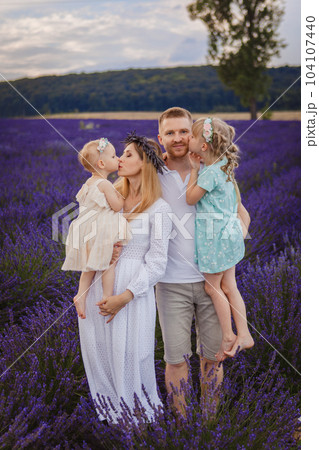 Happy family, father and mother with two daughters on a picnic at lavender field Happy family, father and mother with two daughters on a picnic at lavender field 104107440