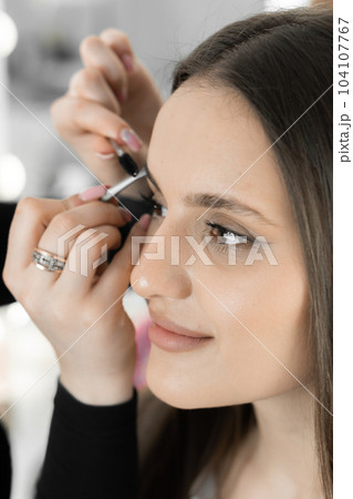 Magical moment makeup artist carefully corrects eyebrows improving look face beautiful woman. Each movement master is professional and fussily working to create perfect eyebrow shape in beauty salon Magical moment makeup artist carefully corrects eyebrows improving look face beautiful woman. Each movement master is professional and fussily working to create perfect eyebrow shape in beauty salon 104107767