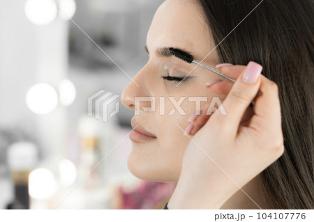 This photo captures the delicate work of the master of cosmetology, who skillfully corrects the shape of the eyebrows. The client can be confident in professional care and perfection of her image. 104107776