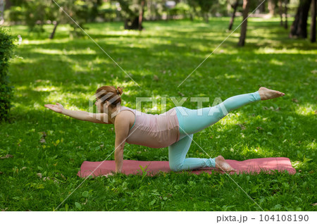 Pregnant caucasian woman doing yoga in the park. Pregnant caucasian woman doing yoga in the park. 104108190