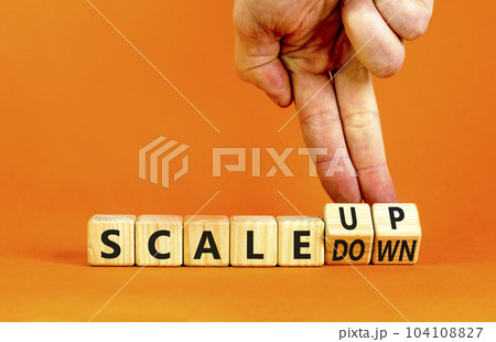 Scale up or down symbol. Concept words Scale up Scale down wooden cubes. Businessman hand. Beautiful orange table orange background. Business scale up or down concept. Copy space. 104108827