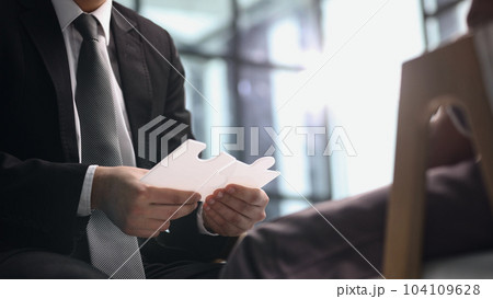 Senior man at office desk connecting jigsaw puzzle parts. 104109628