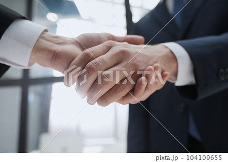 Close up of handshake on blurry conference room interior background. Partnership concept Close up of handshake on blurry conference room interior background. Partnership concept 104109655