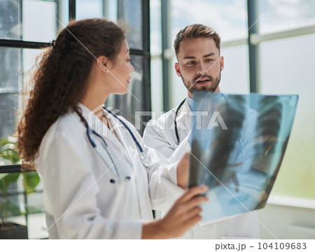 Young serious competent male doctor looking at X-ray at doctor's office 104109683