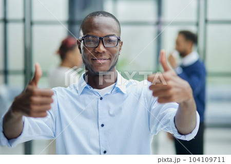 Businessman in glasses showing thumb up while looking at camera Businessman in glasses showing thumb up while looking at camera 104109711
