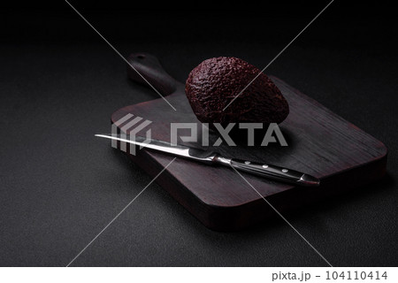 Fresh, ripe, soft brown colored avocado on a dark concrete background 104110414