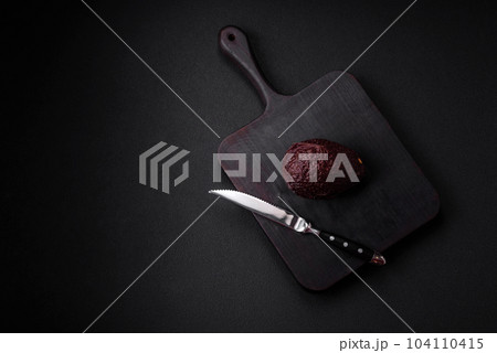 Fresh, ripe, soft brown colored avocado on a dark concrete background 104110415