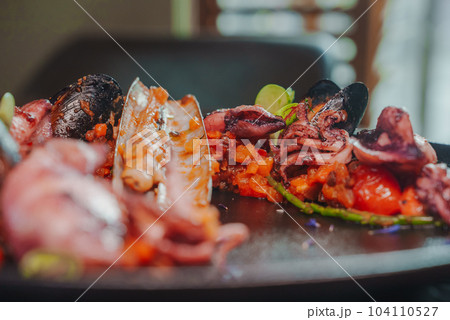 Grilled octopus with calmars, salad and lemon on plate. Close up view. 104110527