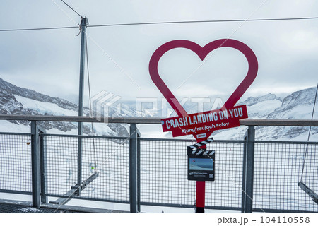 Red heart shape with text by fence with beautiful view of majestic snowcapped mountain and cloudy sky in background at Jungfrau, Switzerland, winter holiday travel concept Red heart shape with text by fence with beautiful view of majestic snowcapped mountain and cloudy sky in background at Jungfrau, Switzerland, winter holiday travel concept 104110558