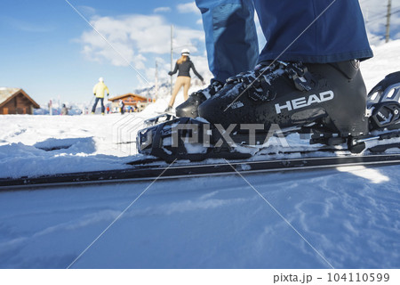 Low section of alpine skier wearing boots and ski standing on snow covered slope at Zermatt, Switzerland, winter holiday travel and sports concept 104110599