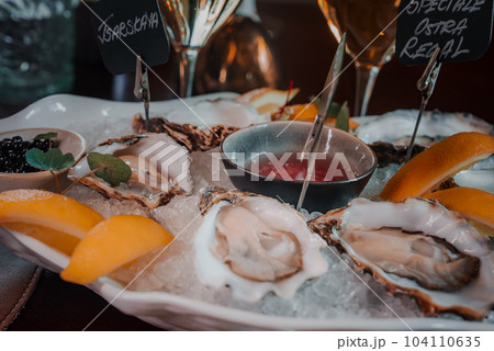 Fresh Oysters close up on a plate, served table with oysters, lemon and ice. Healthy sea food. Fresh Oyster dinner with sparkling wine in a restaurant. Gourmet food 104110635