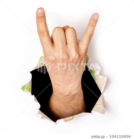 close-up of a hand coming out of a hole in a paper, a rock and roll sign, isolated 104110956