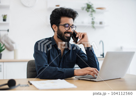 Freelancer talking on phone while using computer at home 104112560