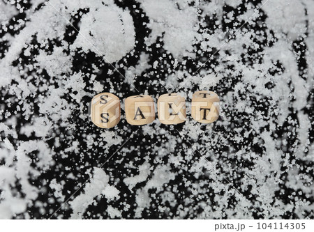 Salt alphabet letter word bead fly with crystal sodium. Less Salty concept to reduce seasoning food. Salt letter word on health care concept. Black background isolated 104114305