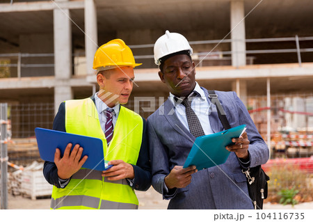 Architect and foreman must write documents and drawings on laptop with building construction 104116735