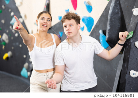 Young woman and teen guy posing near climbing wall Young woman and teen guy posing near climbing wall 104116981