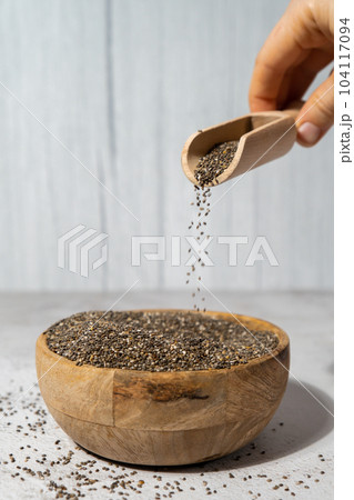 Chia seeds fall in wooden bowl. Healthy superfood rich in Omega 3 fatty acids. Dry healthy natural ingredient. Chia grains are falling Chia seeds fall in wooden bowl. Healthy superfood rich in Omega 3 fatty acids. Dry healthy natural ingredient. Chia grains are falling 104117094