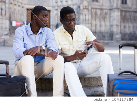 African american travelers resting and using smartphones African american travelers resting and using smartphones 104117284
