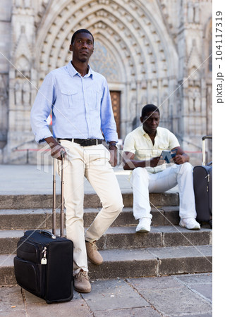 African-american tourists with suitcases on wheels see the sights of city 104117319