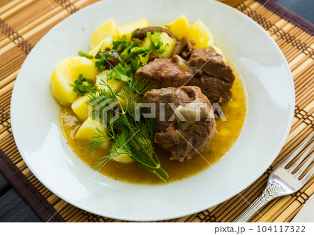 Tasty lamb with mushrooms and potatoes served at plate with greens 104117322