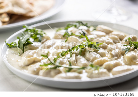 Gnocchi ai quattro formaggi, Italian dough pasta with four types of cheese and ruccola on top Gnocchi ai quattro formaggi, Italian dough pasta with four types of cheese and ruccola on top 104123369