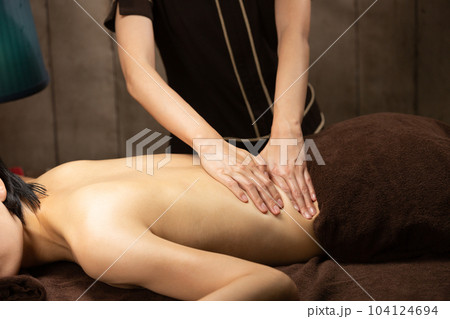 女性は背中のオイルマッサージを受けている。. 女性は背中のオイルマッサージを受けている。. 104124694