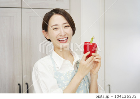 キッチンでパプリカを持つミドルエイジ女性のポートレート 104126535