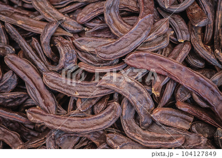 Carob tree pods on a wooden table top view, close-up. Healthy Organic Sweet Carob Pods 104127849