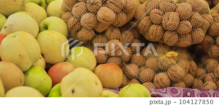 Walnuts and apples on the counter at the farmers market, selective focus on ripe produce, showcase in groceries 104127850
