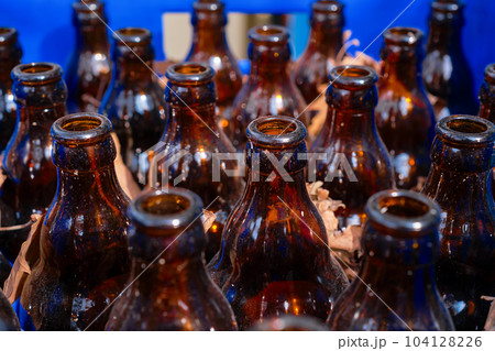 Empty beer dirty bottles in a drawer next to a cafe or bar, selective focus, material recycling and reuse of glass bottles Empty beer dirty bottles in a drawer next to a cafe or bar, selective focus, material recycling and reuse of glass bottles 104128226