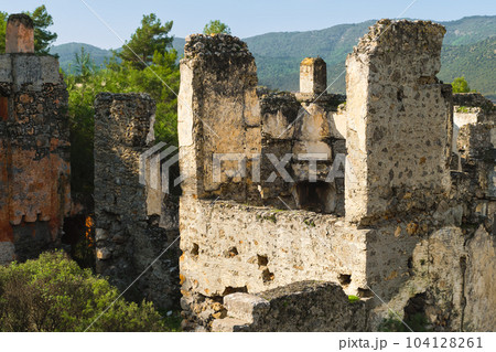 ruins of the abandoned Greek city of Levissi near the village of Kayakoy in Fethiye Turkey, against the backdrop of cumulus clouds, the tragedy of wars. Site of the ancient city of Karmilissos ruins of the abandoned Greek city of Levissi near the village of Kayakoy in Fethiye Turkey, against the backdrop of cumulus clouds, the tragedy of wars. Site of the ancient city of Karmilissos 104128261