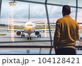 Man in airport departure hall with airplane in background - AI content 104128421