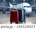 Red and blue rolling suitcase in a departure hall with a passenger plane in the background. AI content 104128423