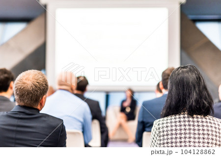Business and entrepreneurship symposium. Female speaker giving a talk at business meeting. Audience in conference hall. Rear view of unrecognized participant in audience. Business and entrepreneurship symposium. Female speaker giving a talk at business meeting. Audience in conference hall. Rear view of unrecognized participant in audience. 104128862