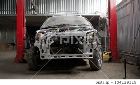 The frame of a powerful white car with body parts removed. Car bumper repair and painting. Disassembled car, in a car repair shop. The frame of a powerful white car with body parts removed. Car bumper repair and painting. Disassembled car, in a car repair shop. 104129319