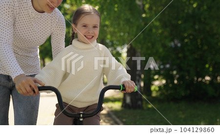 child learn ride bike. mother daughter girl park. happiness smile little child mom. dream family., mother teaches little smiling child ride bike, motherhood childhood, cardio, go faster, concept child learn ride bike. mother daughter girl park. happiness smile little child mom. dream family., mother teaches little smiling child ride bike, motherhood childhood, cardio, go faster, concept 104129860