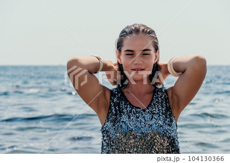 Woman summer travel sea. Happy tourist enjoy taking picture outdoors for memories. Woman traveler posing on the beach at sea surrounded by volcanic mountains, sharing travel adventure journey 104130366