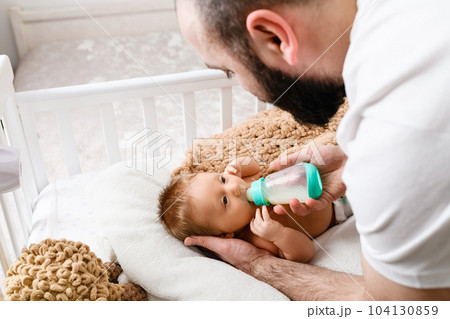 Father feed sleepy infant with baby formula 104130859