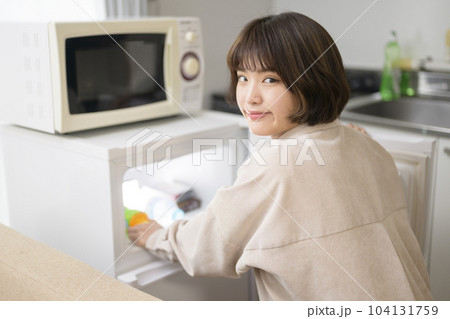 冷蔵庫から飲み物を取り出す若い女性 冷蔵庫から飲み物を取り出す若い女性 104131759