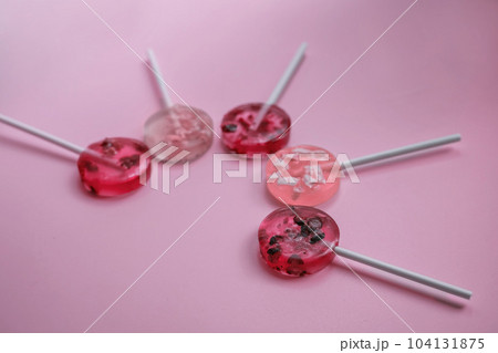 homemade fruit lollipops with pieces of fruit of different shades of pink lie in the shape of a semicircle 104131875