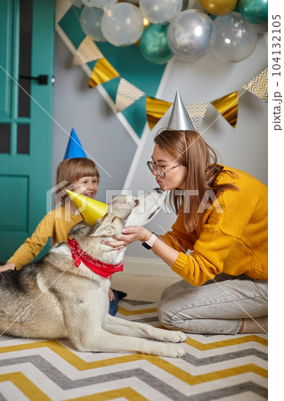 Dog pet birthday, family mother and child hug and kiss their dog congratulating happy birthday Dog pet birthday, family mother and child hug and kiss their dog congratulating happy birthday 104132105